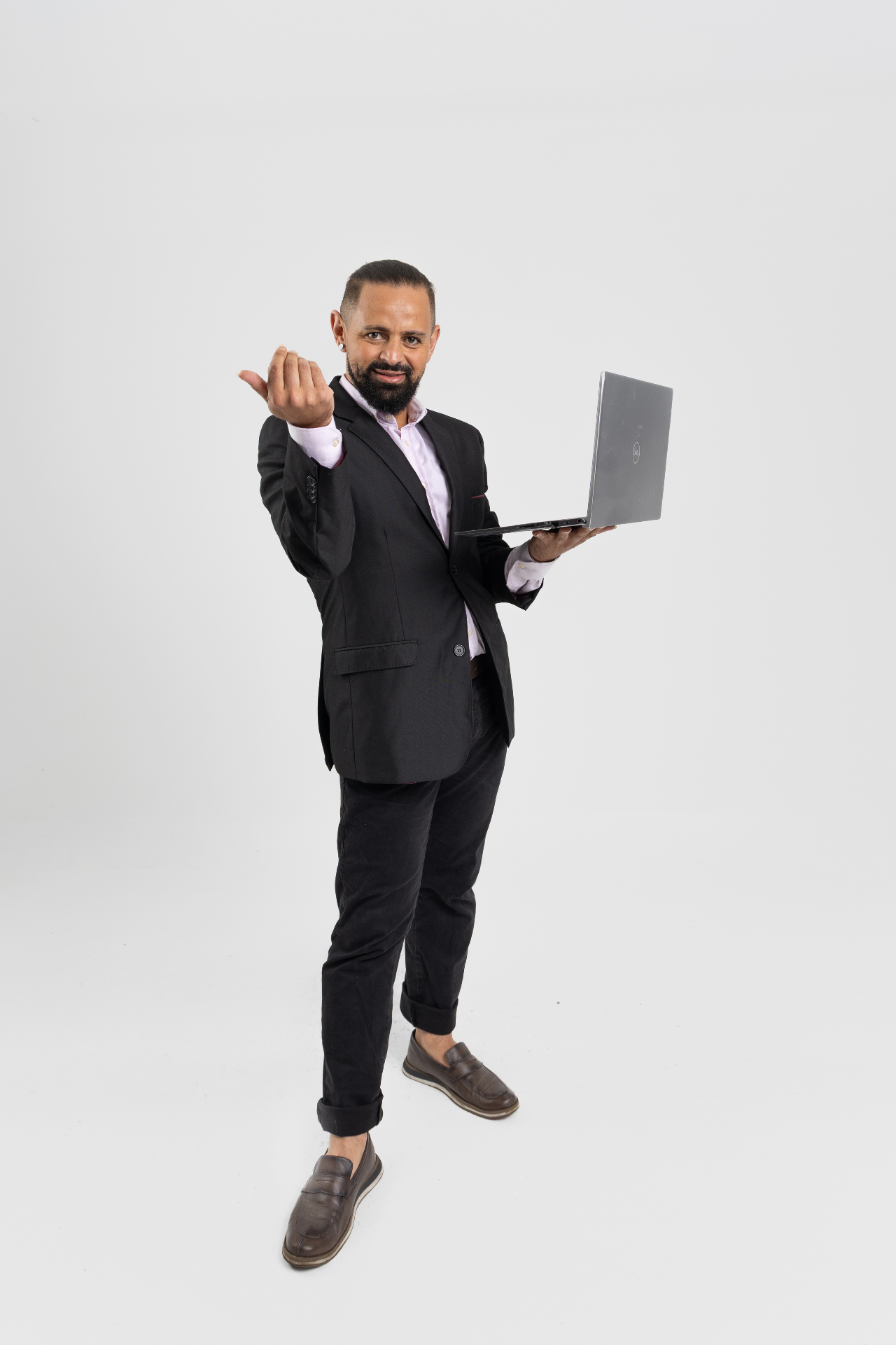 Jayslan Souza usando terno preto, segurando um notebook e fazendo um gesto de convite.