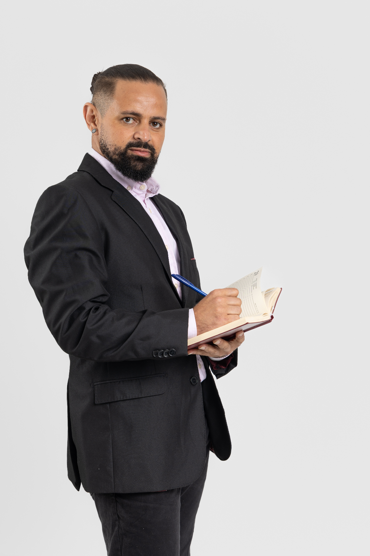 Jayslan Souza usando terno preto e escrevendo em uma agenda.