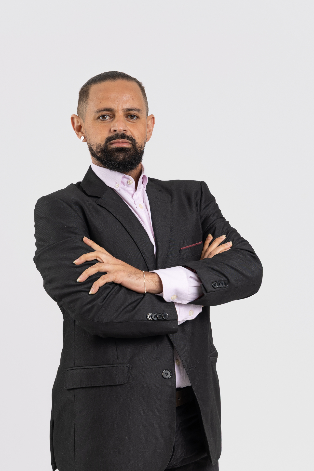 Jayslan Souza usando terno preto e com os braços cruzados em retrato institucional.